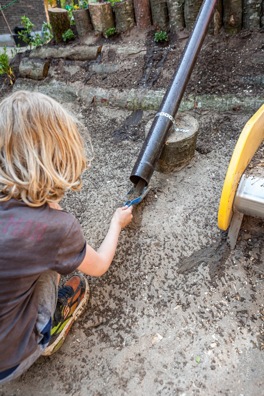 kind speelt met water op een speelheuvel