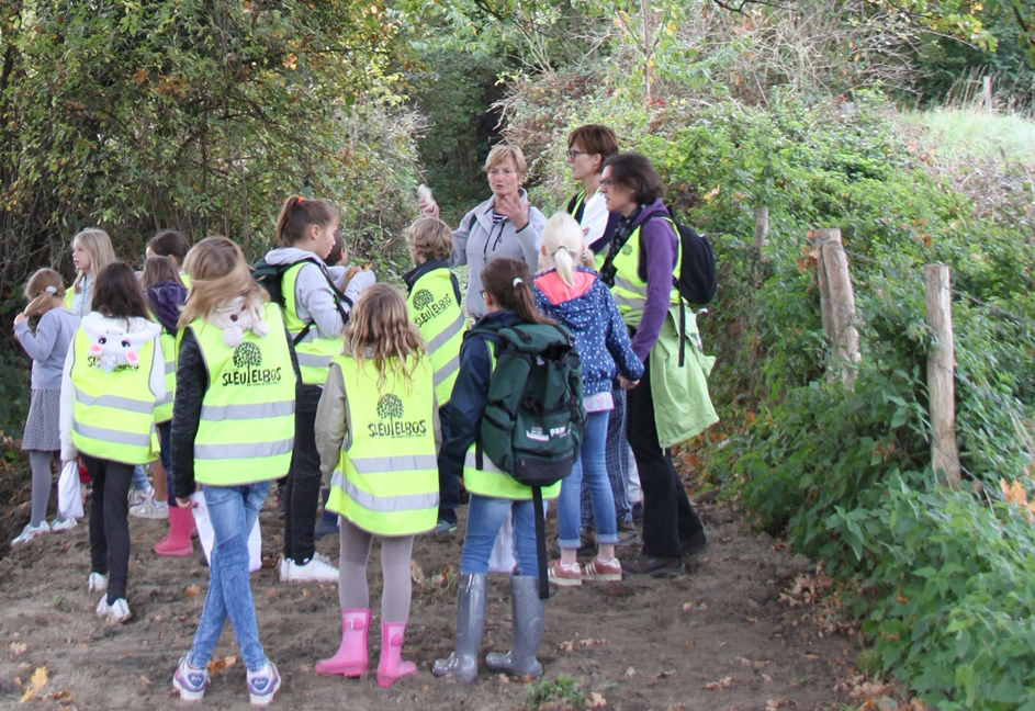 Groep kinderen luistert naar de gids in het bos